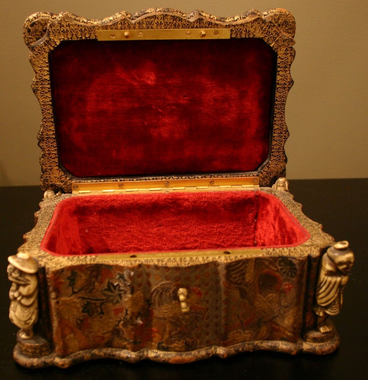 The domed lid with scalloped edge; above a conforming case with corners of Japanese Netsuke ivory figures; the exterior of embossed leather with foliate and bird motif; the interior of red velvet with a plaque reading Susse Fres; Susse Freres or