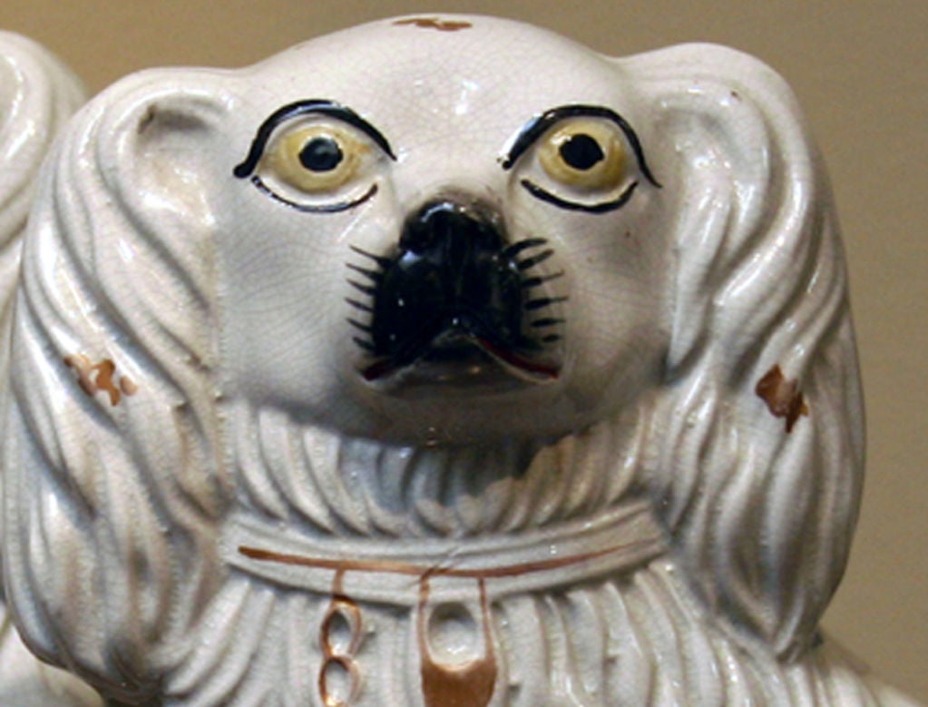 Each modeled after Queen Victoria’s spaniel Dash; the bisque figures are painted white with soft 22 carat gilt chain and collar; Staffordshire ceramics were originally produced by regional folk artists and marketed to the working class.