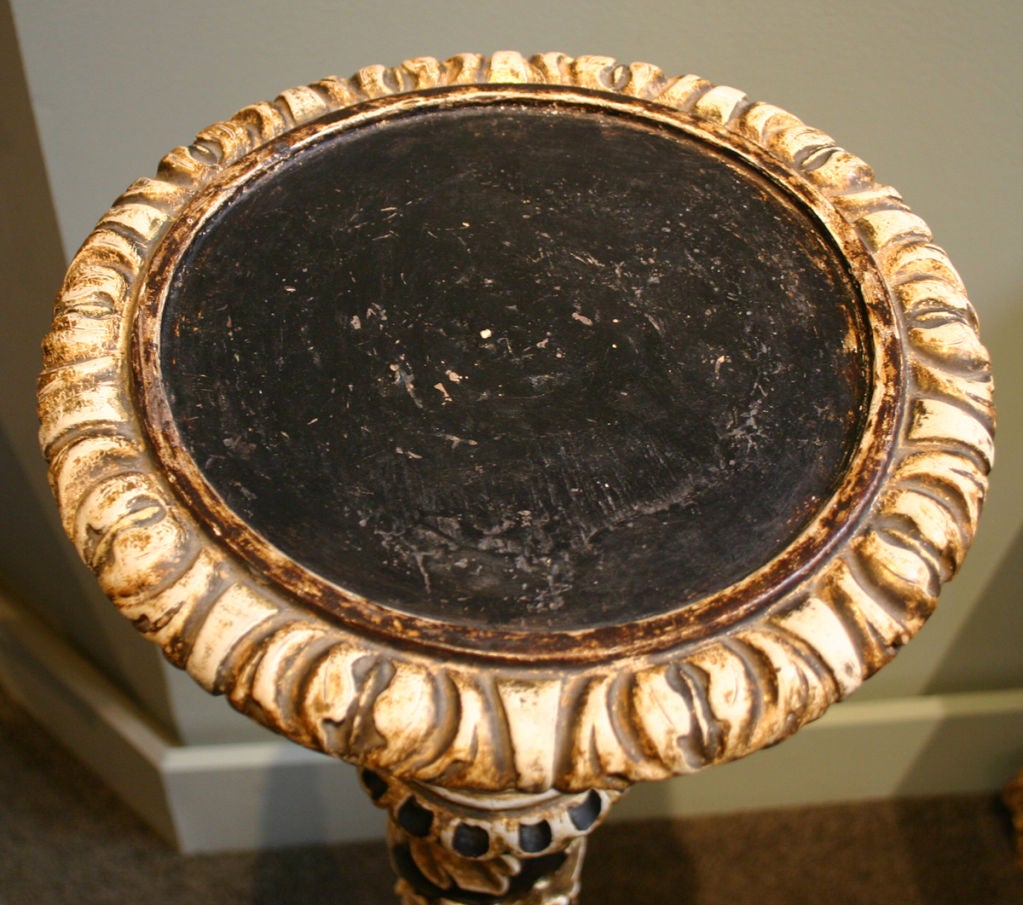 The undulating cylindrical form;  entwined with garland of acanthus leaves; surmounted by a circular top; the whole supported by a round sculpted base raised on tripod griffin feet; retaining original black paint and parcel gilt.