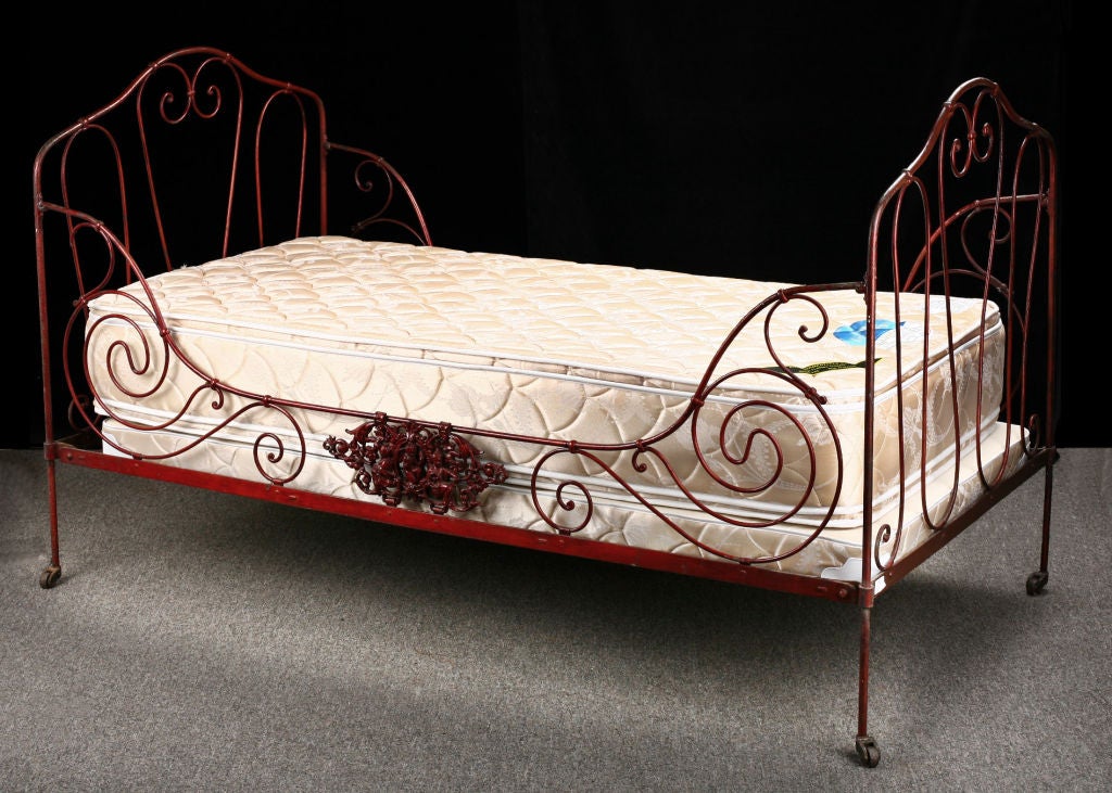 Classic Provencal Forged Iron Daybed with cast iron plaques on both sides.  Slightly smaller than a twin bed. Beautiful red color. Folds down completely, on casters. Custom-made mattress and box spring included.