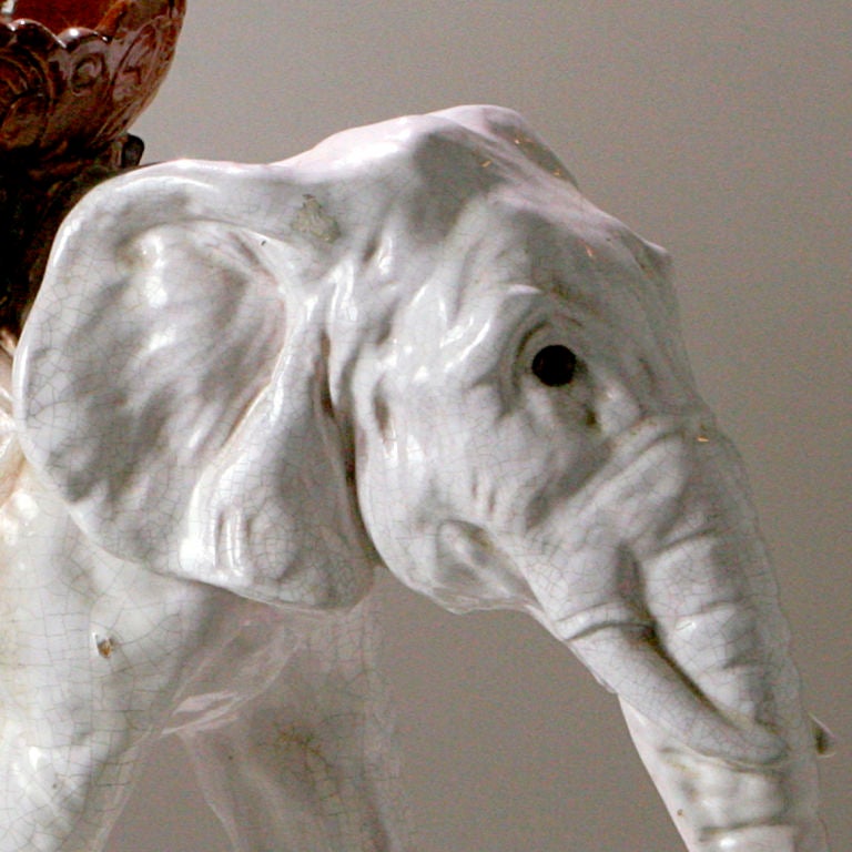 From Normandy, rare extra-large Bavent French Majolica elephant. White glaze finish, two-tone brown woven blanket and ceremonial basket. This charming elephant is sculpted to suggest movement as he strolls with his trunk gracefully curved under.