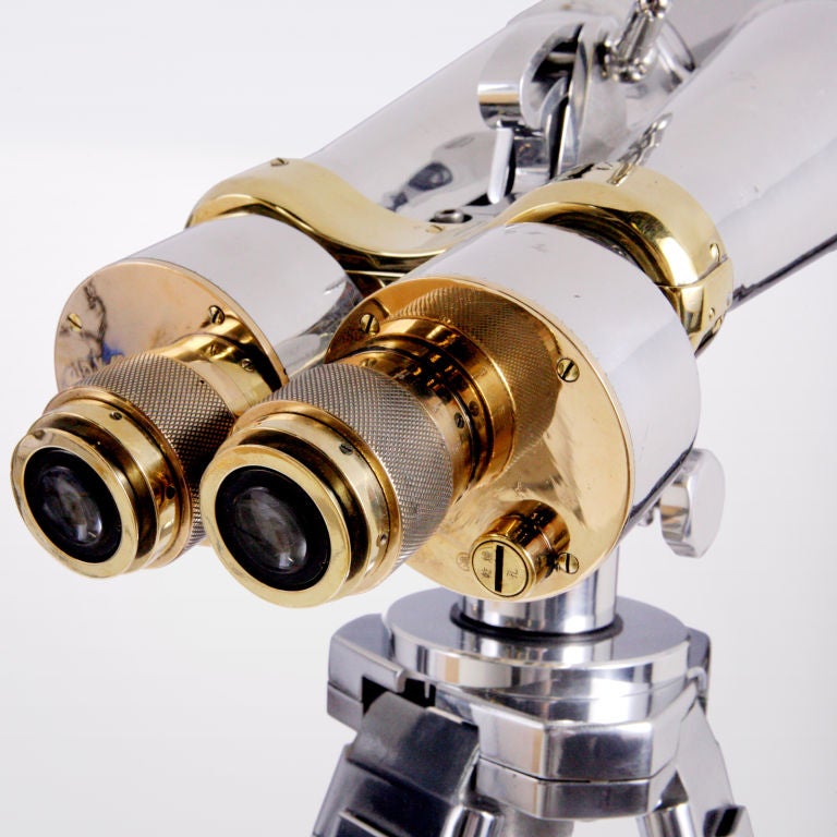 Large standing polished steel naval binoculars.  These powerful  binoculars feature brass covers on the ends of the lenses and brass detailing supported by polished steel tripod legs.  The binoculars have been cleaned and polished with the lens