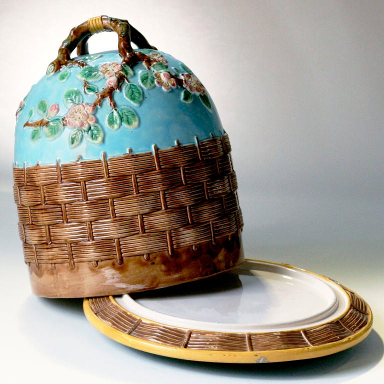 The large size George Jones Majolica cheese bell. Modeled in a basketweave pattern with cherry blossom flowers and woven natural vine handle. On a vibrant turquoise ground. Matching underplate.