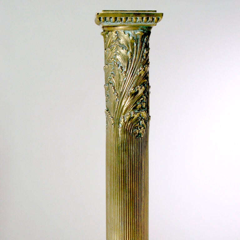 French Neo-Greco brass Chenets designed as tall Classic columns. These stately andirons topped with a swirling acanthus leaf pattern, they taper to a square base supported by beautifully detailed lion paw feet.