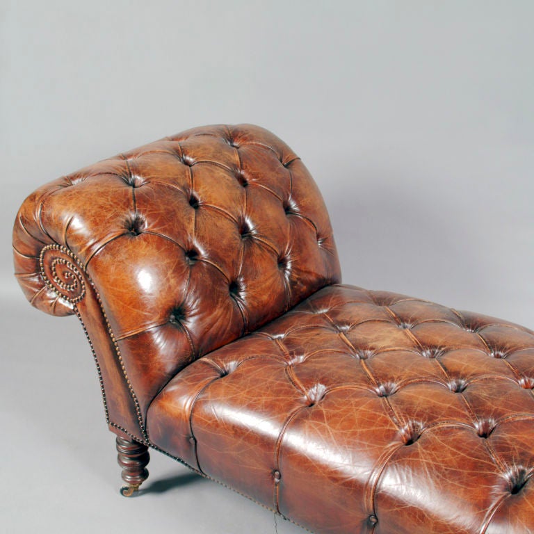 Perfect for a gentleman's library or dressing room, this handsome Victorian leather chaise features tufted button seat and large rolled back.  Outlined with brass tacking and raised on twisted wood feet with brass artillery castors.  Re-upholstered
