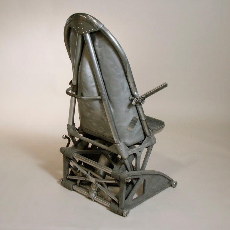 Early WWII British fighter pilot seat.  This unique collectors item was once used by the RAF and features a shaped concave back chair to accommodate the pilot’s parachute.  The aluminum body has been cleaned and polished.  It is impressed with the