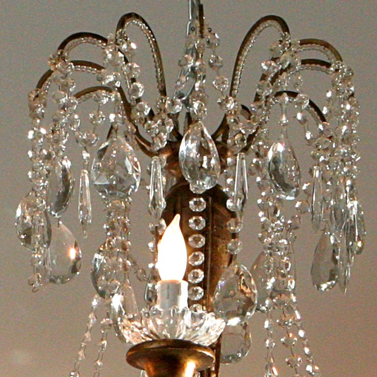 Extra-large twelve light French crystal chandelier.  Features alternating tiers of lights with large pear-shaped crystal drops and beaded roping on a giltwood center piece with bronze arms.