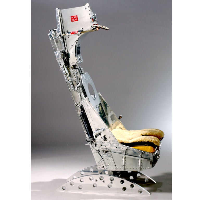 British fighter jet pilot ejector seat in polished aluminum with yellow flotation device.  A collector's item, designed by the Martin Baker Aircraft Company of England, manufactured in 1976 and mounted on a free-standing stainless steel base.