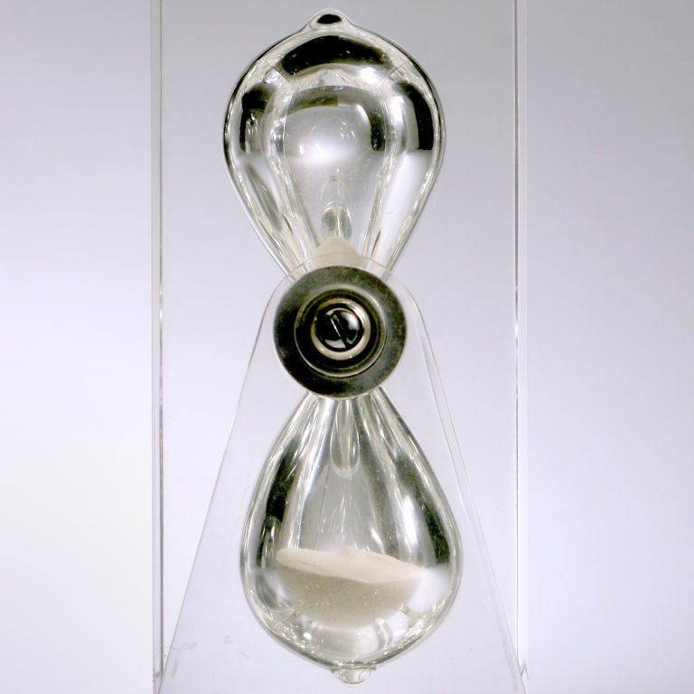 “Frozen in time!”  An oversized vintage Lucite hourglass with the large teardrop shaped sand capsules encased in acrylic glass that is supported by a matching stand.
