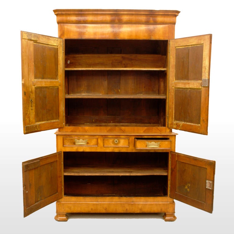 19th century French fruitwood cupboard with inset panels in a chevron pattern outlined with curved mouldings. Twin-paneled upper doors above a two-door lower cabinet that is topped by three narrow storage drawers. Accented with antique brass hinges
