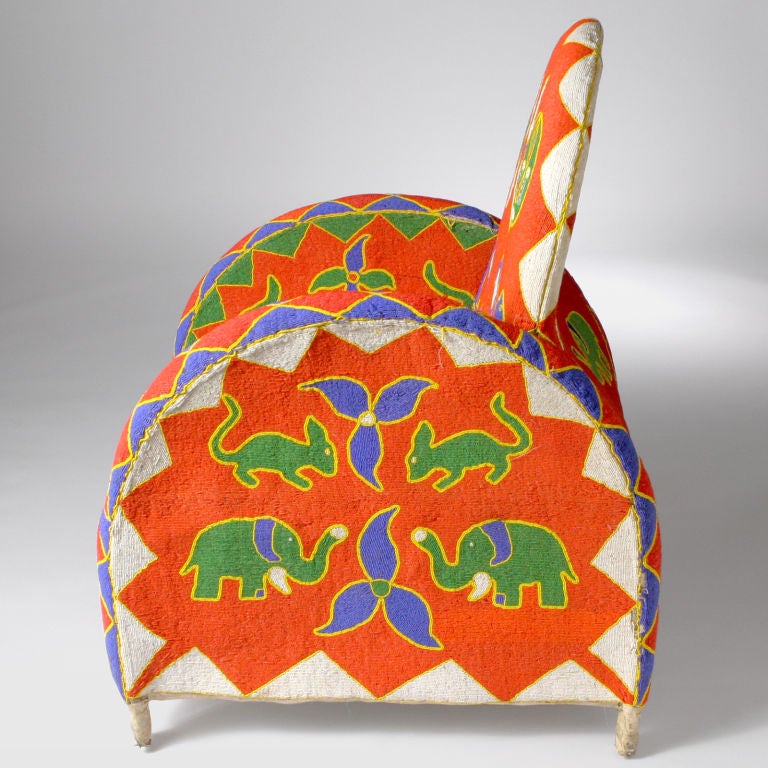 Exquisitely crafted Nigerian beaded armchair in vivid colors with high rounded back and arms.  Completely beaded front, back and sides.  In vibrant patterns depicting African animals juxtaposed with geometric shapes.  Also available with black or