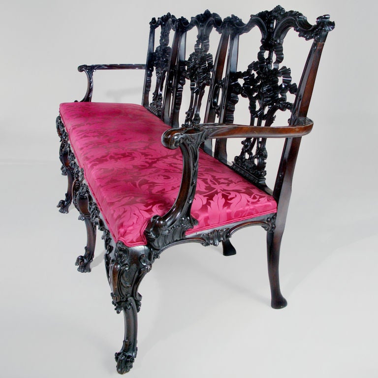 Rare English mahogany settee, delicately carved with a tied ribbon back splat, on scrolled cabriole legs. This tied ribbon style was favoured by Chippendale. The three seat settee, more formal than a sofa was designed to give the appearance of