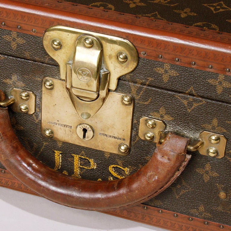 Vintage French Louis Vuitton leather and canvas suitcase with the reinforced brass corners and latch. The exterior with the LV monogram canvas with the leather trim stamped with the LV logo. The interior with buff colored canvas and cotton straps