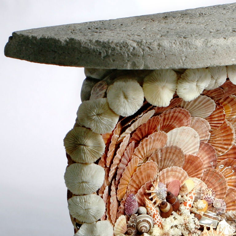 Vintage demi-lune grotto table designed in graceful oval shape on seashell encrusted rectangular base. Created with beautiful naturally colored seashells and coral pieces, the whole outlined with white mushroom coral.  Pitted natural sea stone top.