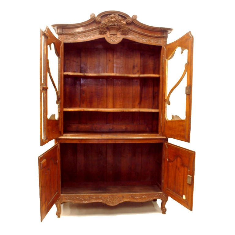 Early French oak cupboard with extra fine carved detailing. Scrolled and flowered lower cupboard doors topped by glass fronted upper cabinet with unique decorative wood scroll piece inset into the glass. The graceful feel carried out with carved