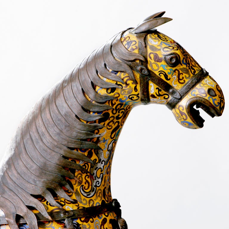 A matched pair of large Chinese cloisonne horses standing on raised wooden platforms. The four-foot high horses each with intricate enameled inlay in traditional Chinese yellow, blue and burgundy color tones. Each horse detailed with long mane and