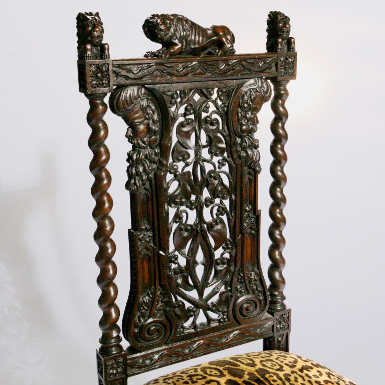 Unique English oak hall chair with small lion figure perched on crest rail.  Ornate carved wood details feature barley twist stiles, carved profiles on upper chair back, open work splat, and ornate curule leg base.  Seat covered in French faux