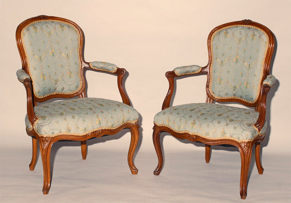 A pair of Louis XV cherry and beech fauteuil signed Poirie (Philippe), c1750, each with a carved crest-rail and seat-rail, the out-scrolled padded arms above the shaped upholstered seat raised on carved cabriole legs headed by floral carved