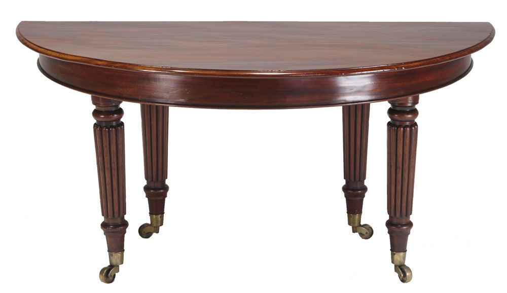 Regency mahogany extending dining table, c1815, the circular top divides to become two free standing consoles or extending to support four extra leaves, two original and two later, above a plain frieze the whole raised on eight reeded, turned and