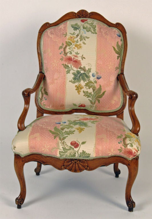 Late Régence, Early Louis XV beech fauteuil à la reine, c1720, the top arched rail with beautiful rocaille carving, continuing to the down swept, reeded and scrolled arms above a serpentine, generous upholstered seat surrounded by a carved stretcher