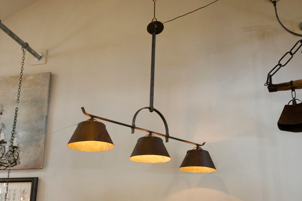 Apparecchio in ferro forgiato a mano con tre paralumi in ferro. Dettagli in rivetti sui lati delle tonalità.  È ideale sopra un'isola della cucina, un tavolo da pranzo o una sala da biliardo. Il design si basa su una lampada appesa nel Dayton