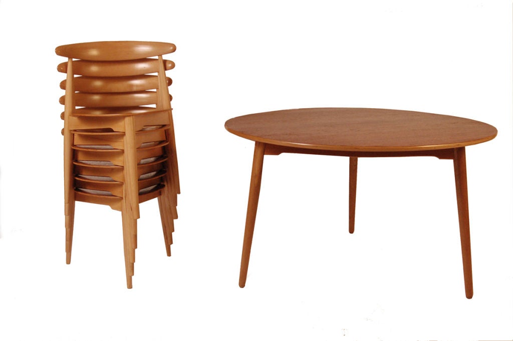 Set of six three legged chairs, teak plywood seat and beech frame. Table teak top with oak base. Three legged table holds two chairs in each section. Made by Fritz Hansen.