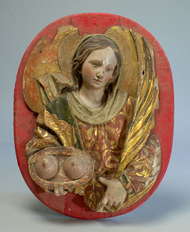 Saint Agatha, patroness saint of breast cancer, earthquakes and natural disasters, is represented in this 18th century Spanish colonial plaque with her excised breasts on a platter. Carved and polychrome painted wood with elaborate 'estofado' gold