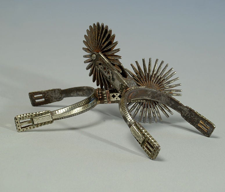 A pair of very fine 19th century silver inlaid gaucho spurs from Argentina. Large 32 point, 3.5 inch rowels and 3.75 inch heel band openings. Beautiful silver inlaid chevron patterns with copper shank inlays. Excellent surface patina and wear