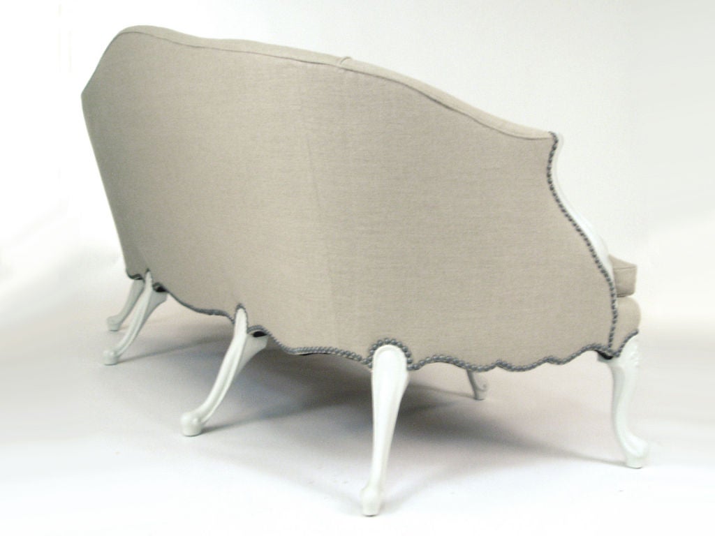 An early 20th century, graceful curved frame with elegant hand carved legs. Down seat cushion. Beautiful pale grey linen upholstery. Nickel nailheads.