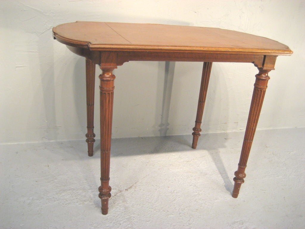 This writing table, made of walnut, has a leather top and stands on fluted and turned legs. <br />
For many more fine antiques, please visit our online gallery at: www.ofleury.com