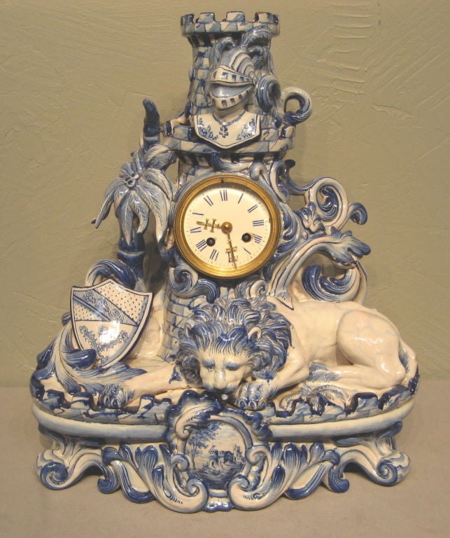 A superb mantel set from St. Clement in blue and white faience. This elaborate, sculptural clock is flanked by a pair of regal lions, and is in good  working condition. Exceptionally painted and detailed with hands that form of the cross of