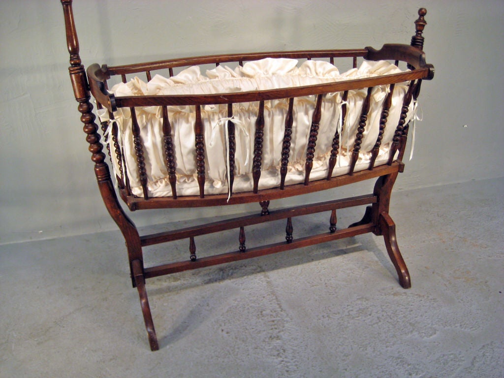 Baby cradle from the Provence region, made of beechwood with nicely turned spindle rails and lined with silk. The cradle gently rocks on the sturdy frame. More French Antiques at www.ofleury.com