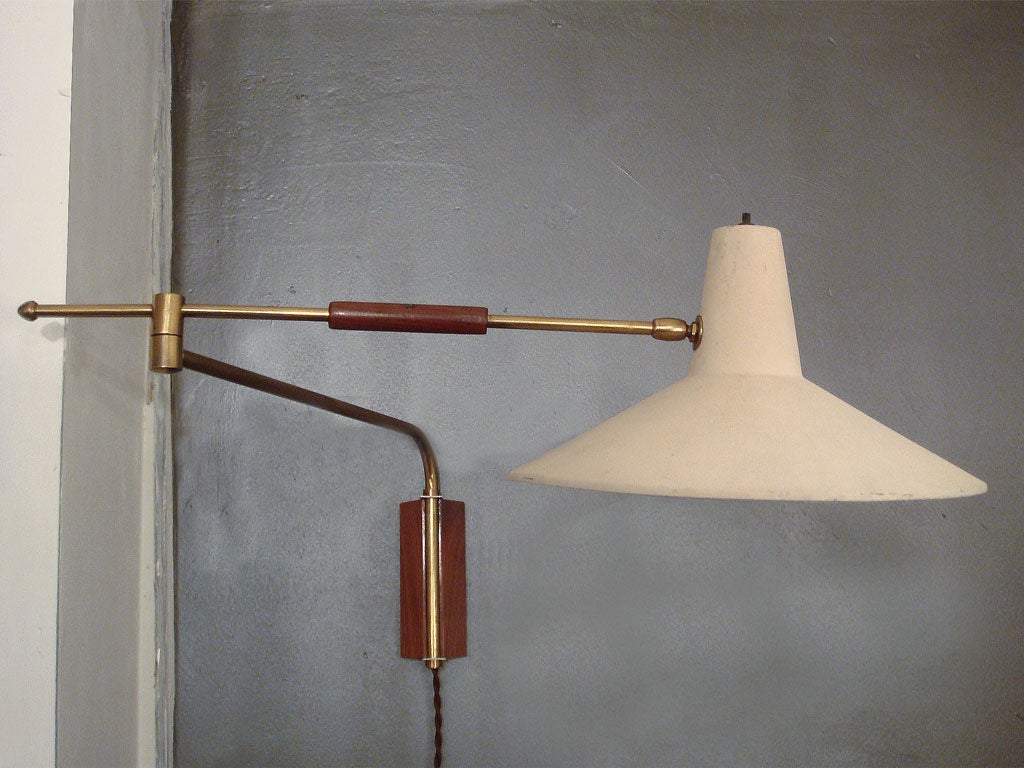 adjustable swing-arm wall light with cream colored enameled metal hood<br />
brass arms and wood detail <br />
arm lengths 19