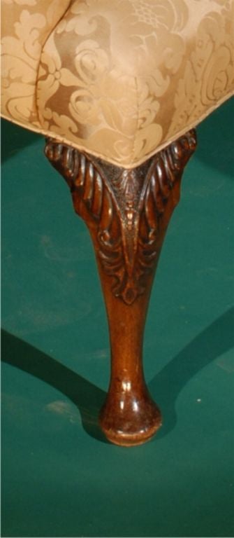 AN ANTIQUE ENGLISH, GEORGE II WALNUT LIBRARY (GAINSBOROUGH) ARM CHAIR STANDING ON CABRIOLE LEGES HAVING FOLIAGE CARVED KNEES DATING CIRCA 1730