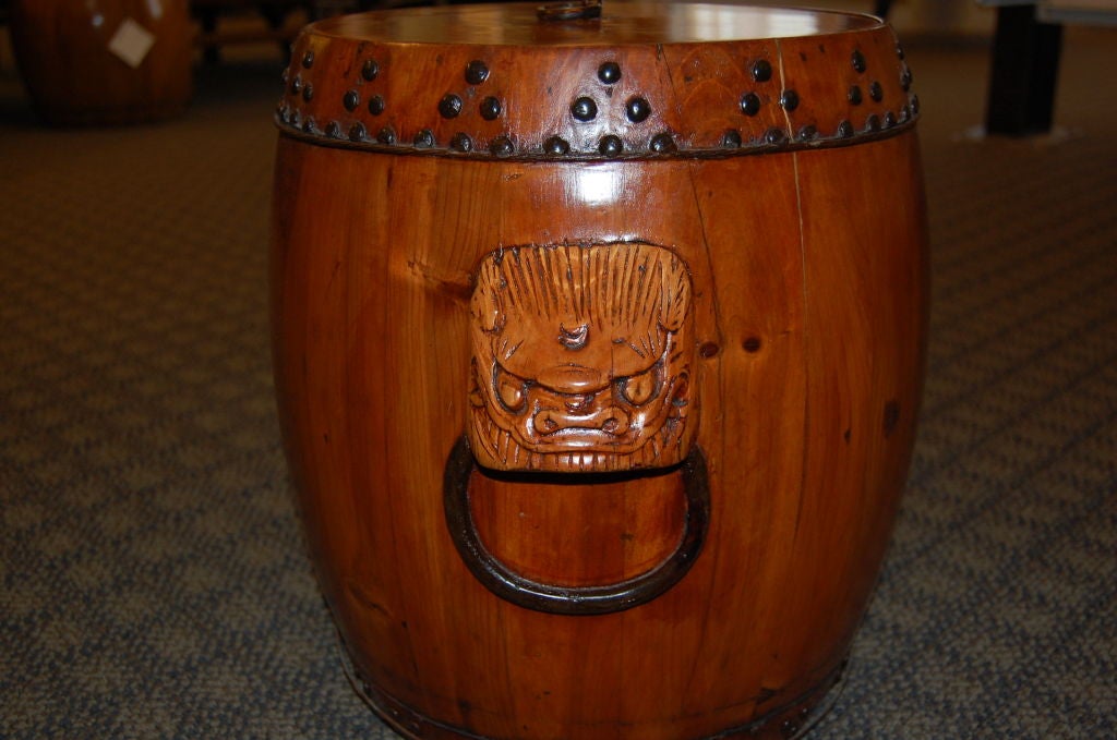 A decorative and useful wooden rice storage container with removable lid.  <br />
<br />
There are borders made of metal rivets, and wire bands at top and bottom.<br />
<br />
Each side has a stylized dog holding a ring in it's mouth, as