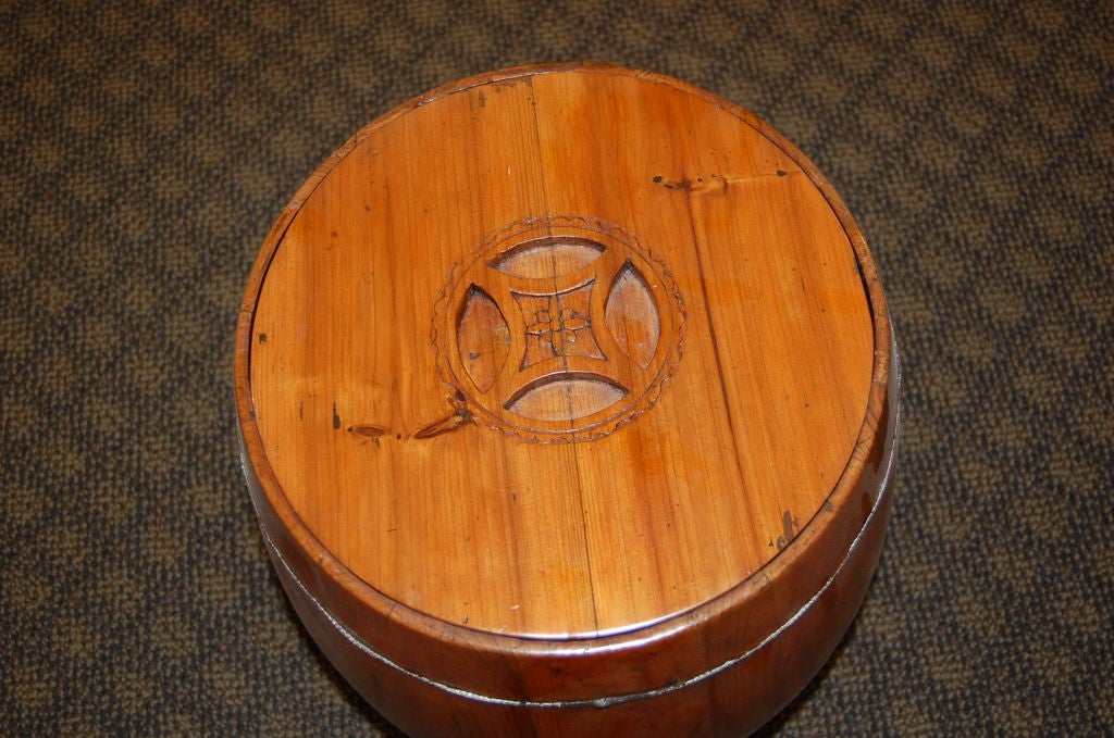 A simple Chinese wooden rice barrel with removable lid, circa 1900, with metal wire bands at top and bottom.