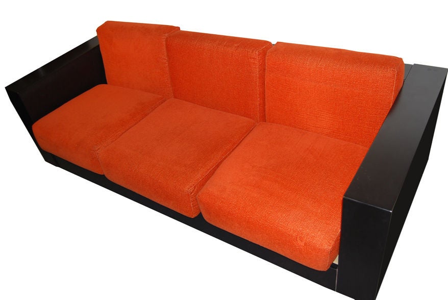 A three seat modernist sofa, model Saratoga, featuring a floating cubist body in black lacquered wood which sits on a square base. The sofa also features two piece seat and back rests with original deep orange textured upholstery. By Massimo and