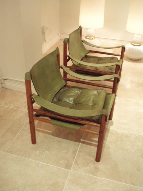 A pair of safari chairs each featuring frames in Rosewood with armrest slings, back and seat slings and a tufted seat cushion in green leather. Brazilian circa 1965.