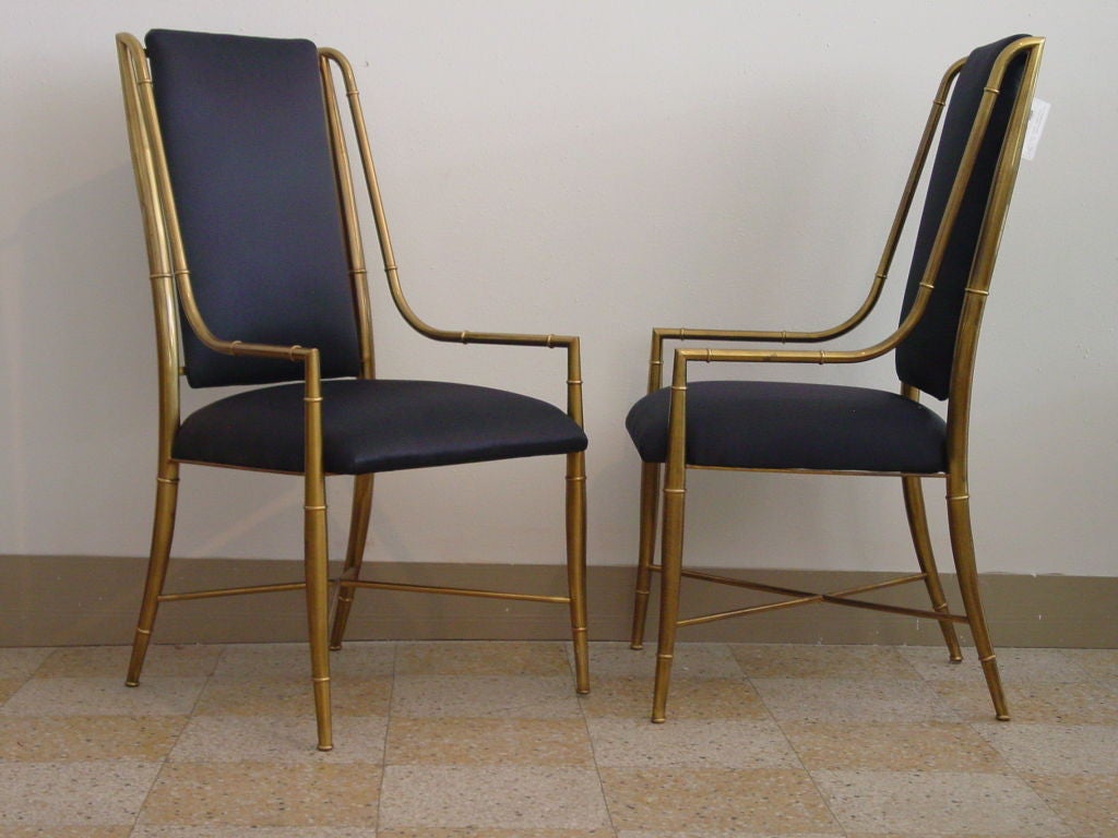 Six brass bamboo motif chairs with low open arms.  New black metallic denim upholstery. Incredibly chic.