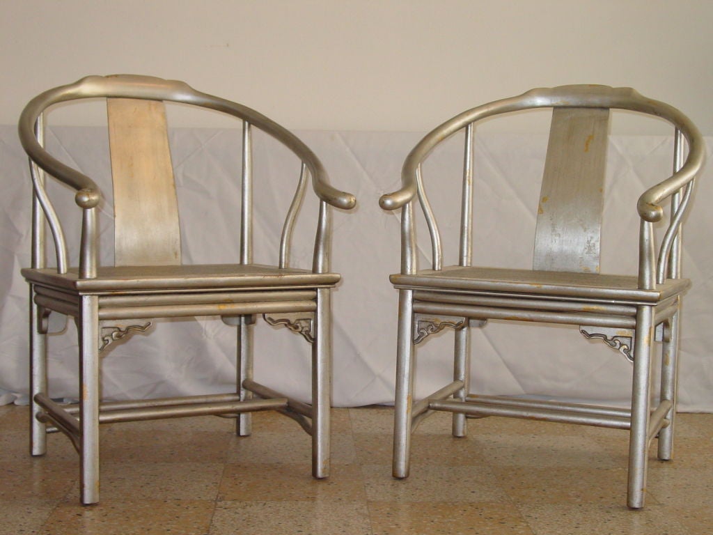 Pair of Asian inspired chairs in silver leaf with random patches of gold.  Cane seats in excellent shape.  Very much in the manner of James Mont, both in design and finish.  Two pair available.