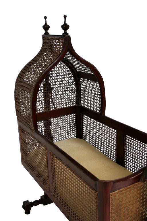 A Victorian cane-filled hanging bassinet with peaked hood.