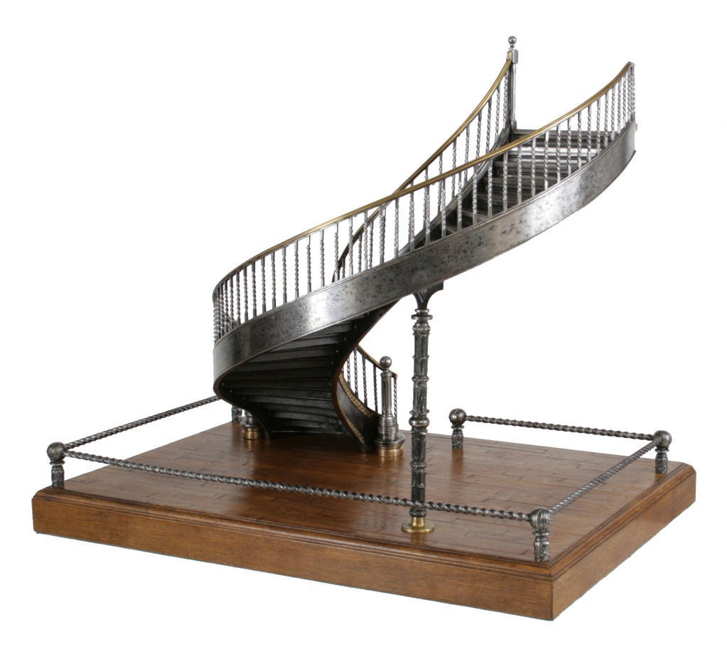 A generously-scaled late 19th century polished, cast, and wrought iron and brass-mounted model of a spiral staircase with a balustraded gallery and oak parquet base.