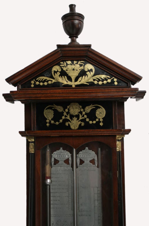 Dutch mahogany, ebonized and verre eglomise barometer with ebonized pilasters with brass capitals and pewter register plates,surmounted with an arched cornice with an urn finial.