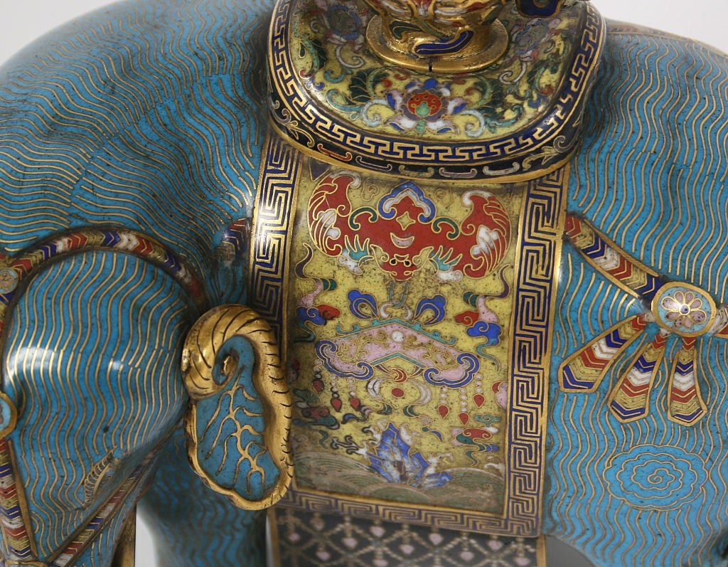 A pair of Chinese Quing Dynasty (l.18c-19th c.) cloisonne enamel elephants, with studded multicolored trappings to the head and draped over the back with tasseled blankets and with baluster vases atop the howdah, the turquoise body with overall gilt