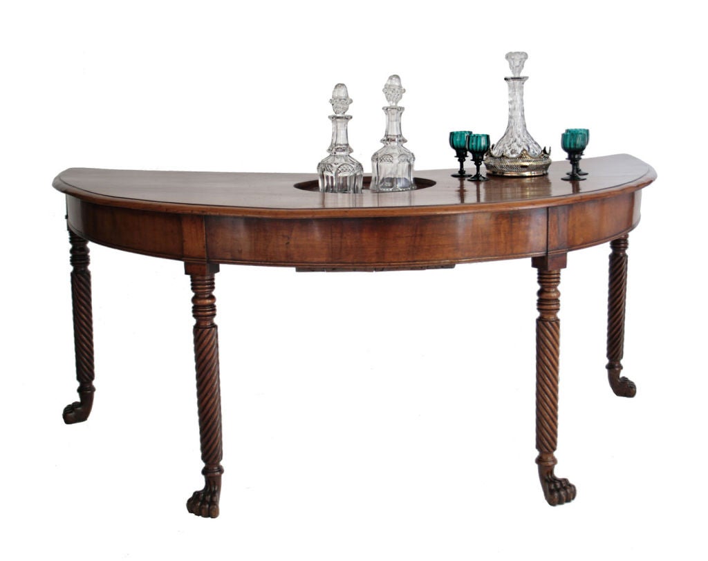A Regency faded mahogany crescent-form wine tasting table, the top with concealed recessed bottle caddy, on spiral carved legs.