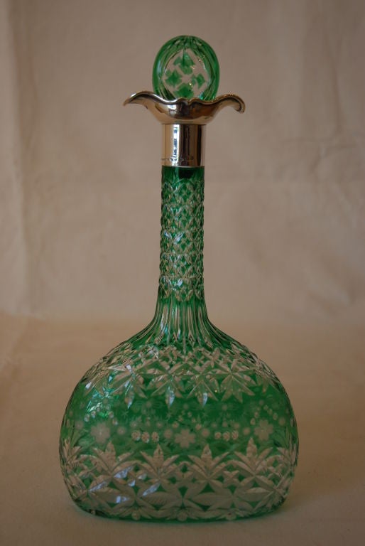 An elaborately cut green glass decanter and stopper, the long neck mounted in silver, made in 1906; and another decanter and stopper, with overlaid green spiral decoration, made in 1901, from $2850.00.