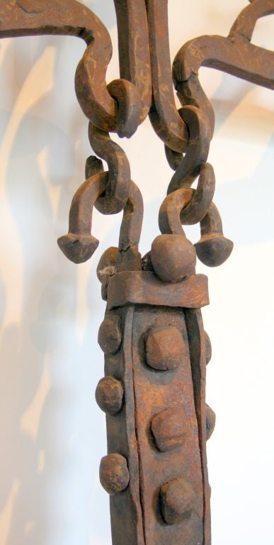 This gorgeous and fascinating Medieval cremaillere is all incredibly hand-forged iron. It was made to be placed in front of the fireplace of a castle. In the center is an adjustable pot hook, two cranes, torch-holders, etc. This exquisite piece most