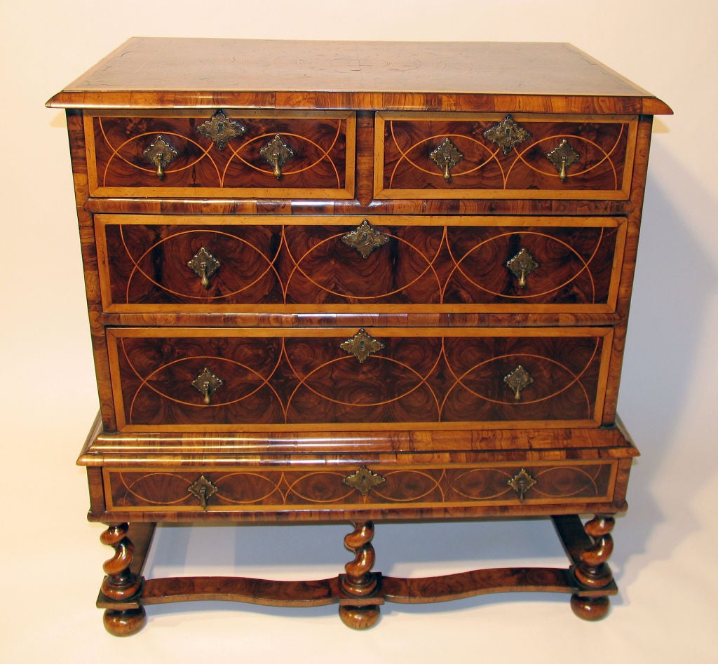 Circa 1690. A rectangular crossbanded top with molded edge and circular inlay is above two short and two long drawers inlaid sympathetically with the top and sides; on a short stand with one long inlaid drawer raised on six barley twist turned legs