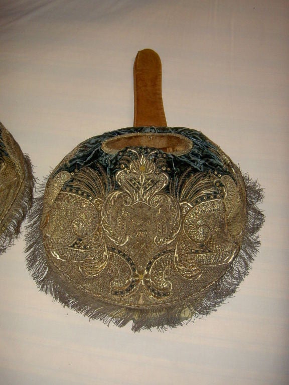 The circular-form velvet ground backed by leather and applied with gold and silver metal fringe and threads, decoration centering a cuirass