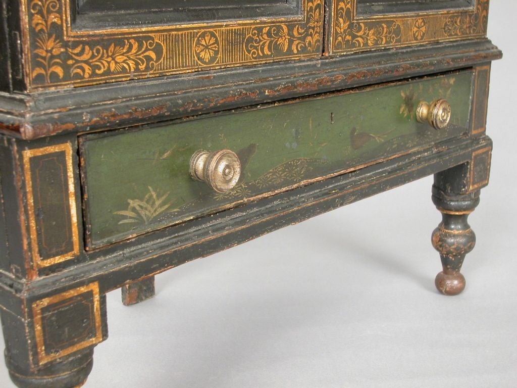 A very rare Sheraton/Regency period green lacquered corner cabinet with original decoration and surface. The doors and working drawer below are decorated Chinese scenes of nature bordered by stylized neo-classical gilt decoration. The case rests on